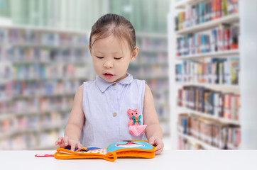 Wall Mural - Little asian girl reading book in library