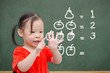 Little asian girl counting her finger in font of chalkboard