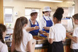 © Monkey Business - Two women serving kids food in a school cafeteria, back view
