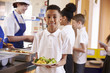 © Monkey Business - Mixed race boy holding a plate of food in a school cafeteria