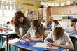 © Monkey Business - Primary school teacher helps a pupil at desk with classwork