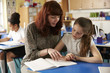 © Monkey Business - Teacher helps a girl at her desk, close up both looking down