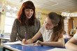 © Monkey Business - Primary school teacher helping with classwork at girl’s desk