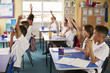 © Monkey Business - Pupils raise hands in a lesson at primary school, side view