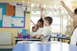 © Monkey Business - Primary school children raising hands in class, low angle