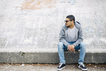 Young Man Sitting On A Wall Wearing A Hoodie