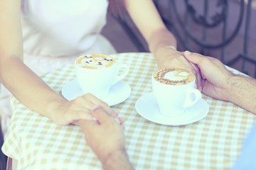 Wall Mural - Loving couple holding hands on table in cafe