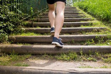 Close up of young man legs running up the stairs in a city park.Runner man Practice training on stairs in a city park.