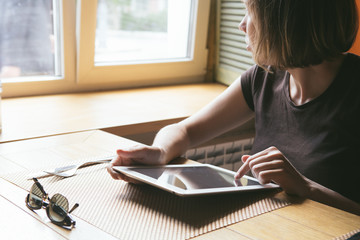 a young girl works with the tablet at the window