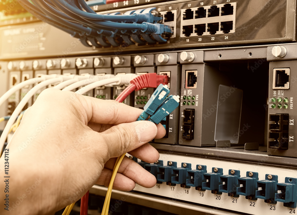 man working in network server room with fiber optic hub for digi