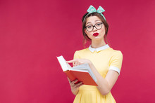 Serious Young Woman In Glasses Standing And Reading A Book