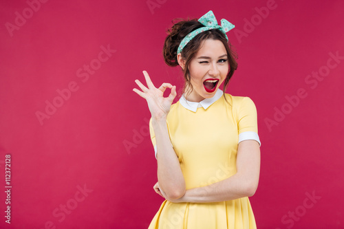 Happy attractive pinup girl in yellow dress showing ok sign Canvas Print