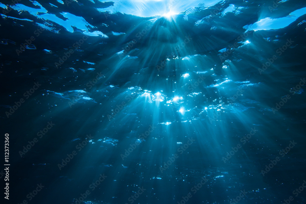 Underwater shot with sunrays in deep blue tropical sea - obrazy, fototapety, plakaty 