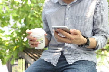 Wall Mural - Man using smartphone with holding coffe paper cup