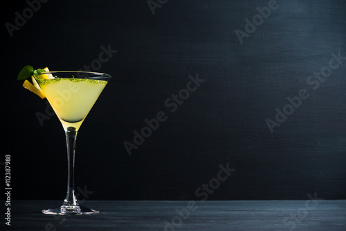 Fotografía Cóctel de martini de color amarillo con el limón y la menta en el fondo de mader