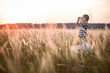 © goodmoments - Boy seaman floats on a sailing boat in the field at sunset on a warm evening summer. Dreams of travel! Child floats on a handmade boat against the backdrop of a sunset.