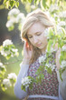 © goodmoments - Portrait of a young smiling woman looking at apple trees' flowers. Girl and blooming apple tree. Spring time with trees flowers.