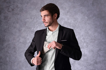 Poster - Attractive man hiding dollar banknotes in suit on grey background