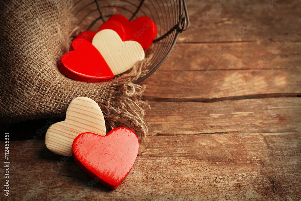Wooden hearts in wicker basket, on rustic wooden background
