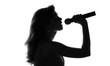 silhouette of a woman singing with a microphone in hands