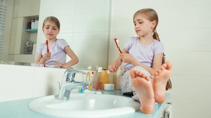 portrait girl using toothbrush and cleaning teeth. girl looks at their teeth sitting near the mirror
