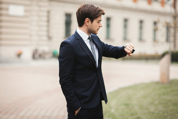 Confident businessman looking on his wrist watch in suit