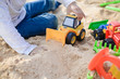 Kid having fun outdoors happy playing with his truck toys on a sunny summer day background sandy