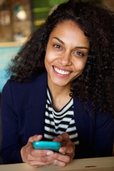 Wall Mural - Smiling woman sitting at a cafe table with cellphone