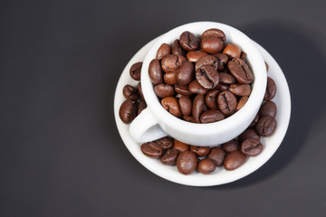 white cup full of coffee beans on black background