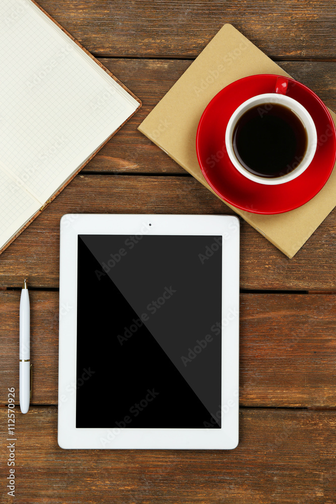 Digital tablet with cup of coffee and notebook on wooden table, closeup