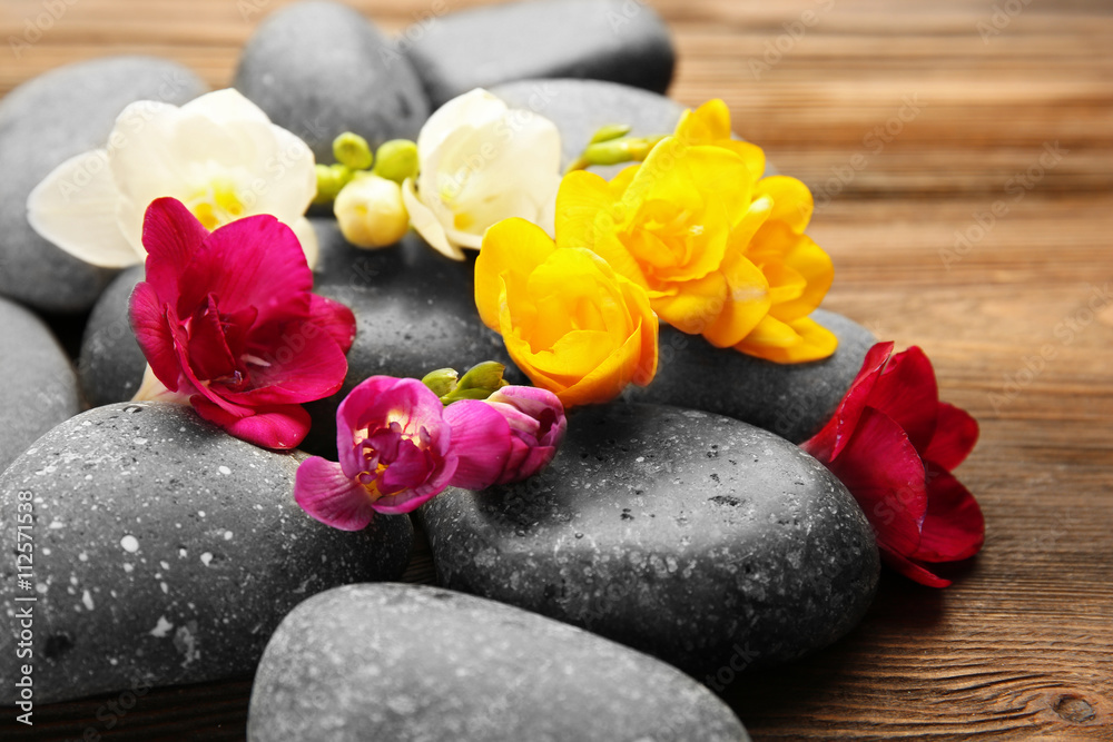 Beautiful spa composition with stones and freesia on wooden background