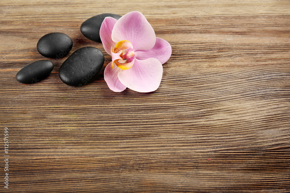 Spa stones and orchid flower on wooden background