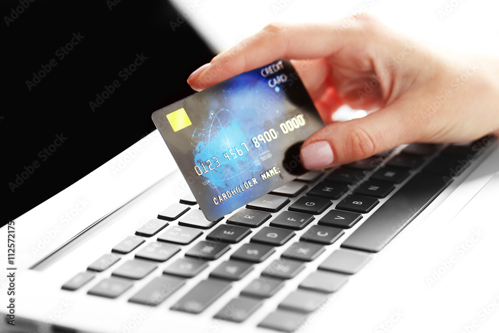 Hand holding plastic credit card and using laptop. Online shopping concept.