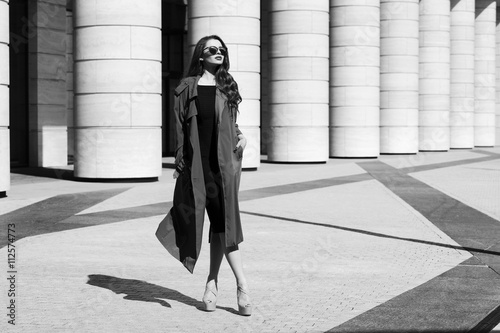 Mode mode style portrait dynamique de jeune belle belle femme posant à la rue de la ville en robe noire, manteau gris et lunettes de soleil Tableau sur Toile