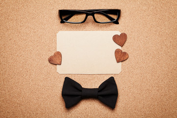 Wall Mural - Spectacles, bowtie and empty paper blank in Happy Fathers Day, cork board background, top view, flat lay