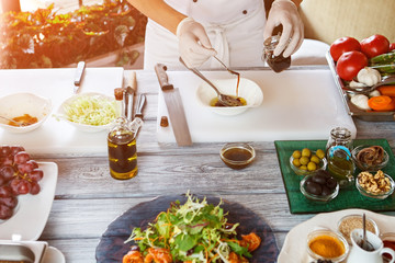 Wall Mural - Hands holding spoon and jar. Sauce pouring into bowl. Chef mixing food ingredients. Gourmets will be happy.