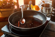 Pan with liquid and spoon. Cinnamon stick and dark liquid. Wine sauce with cinnamon. Sweet aroma and taste.