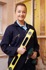 Wall Mural - Portrait Of Female Builder With Spirit Level And Electric Drill