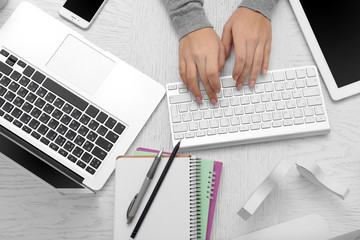 Wall Mural - Woman hands at table with computer, tablet, smart phone and other things, top view