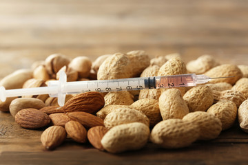 Allergy food concept. Nuts with syringe on wooden background