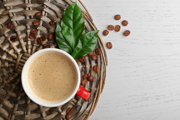 Poster - Cup of coffee with beans and leaves on wicker background