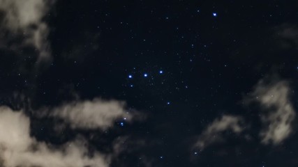 time lapse in 4k of the stars of constellation orion moving in the background of night clouds illumi