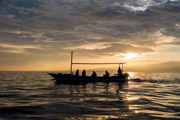 Wall Mural - Amazing sunrise with silhouette of people in small boat in Lovin