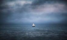Sailboat On Ocean Under Storm Clouds