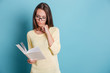 © Drobot Dean - Beautiful pensive young girl reading book over blue background