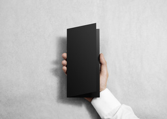 Fototapete - Hand holding blank black opened brochure booklet in the hand. Leaflet presentation. Pamphlet hold hand. Man show flyer offset paper. Sheet template. Booklet design. Paper display read first person