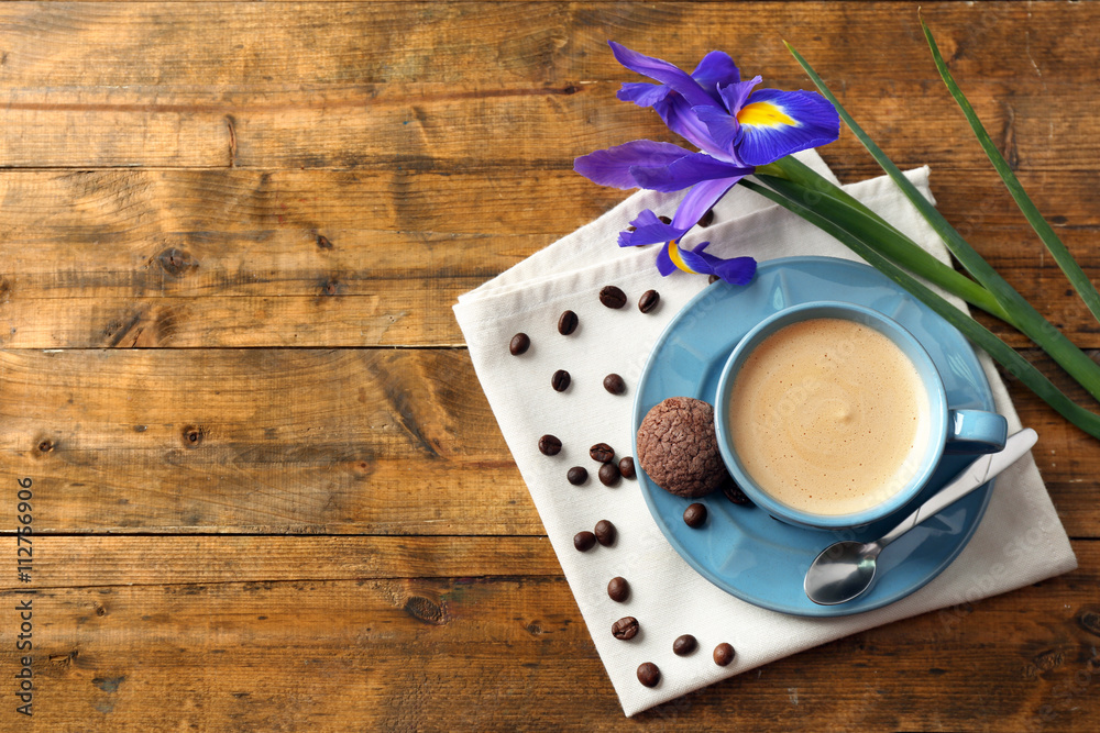 Cup of coffee with irises on wooden table