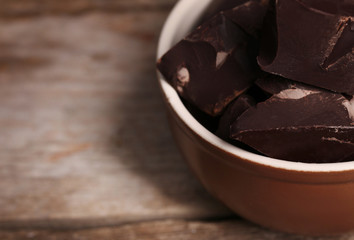 Wall Mural - Chocolate bar pieces in a bowl on wooden background