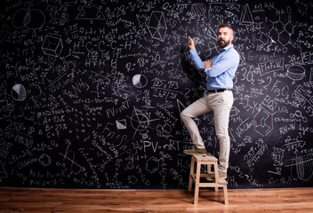 Man writing on big blackboard with mathematical symbols
