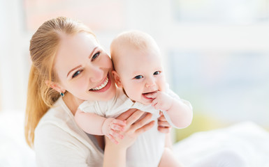 happy family mother with baby playing and hug in bed